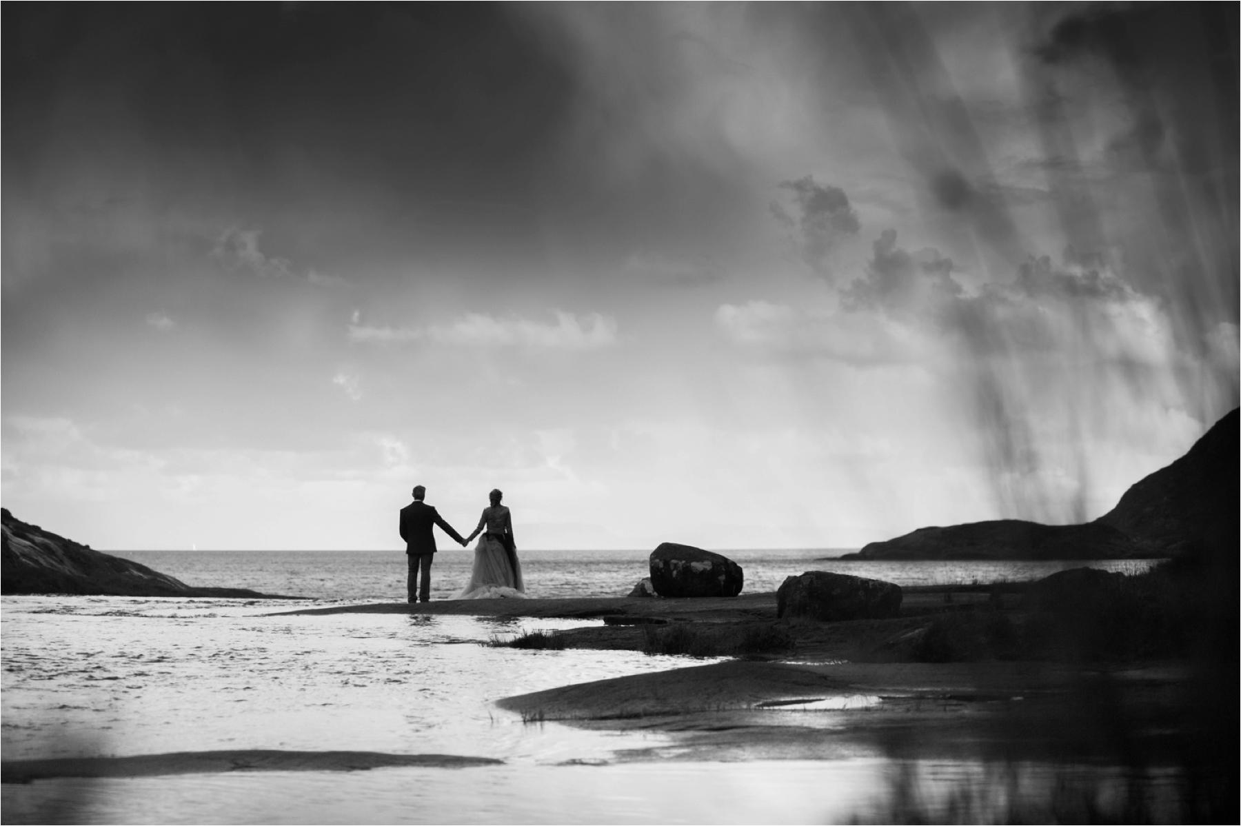 Rain heads toward the bride and groom in this black and white wedding photo, adding drama as well as a drenching. 