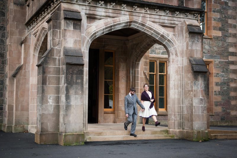 Old stonework frames this photo of an excited bride and groom on their wedding day at Lews Castle on the Isle of Lewis.