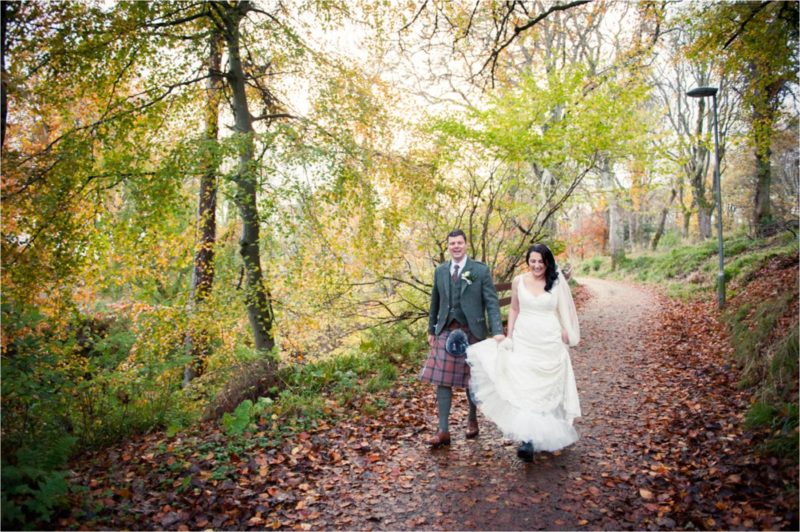Green trees surround the bride and groom as they walk through the grounds of Lews Castle on the Isle of Lewis in the Scottish Highlands.