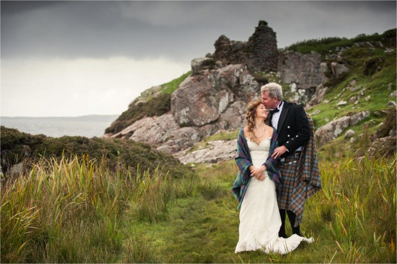 A groom kisses his new wife's head after their wedding at Dunscaith Castle on the Isle of Skye in the Scottish Highlands.