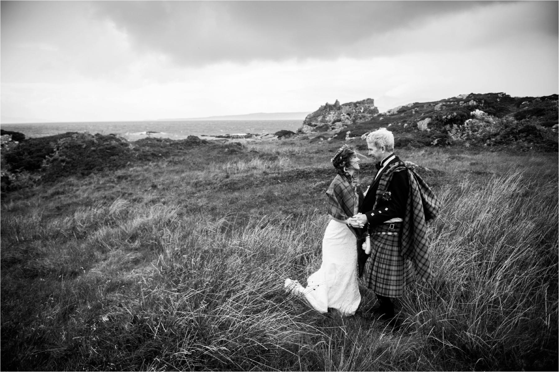 Black and white photo of a bride and groom near Dunscaith Castle on the Isle of Skye in Scotland. 